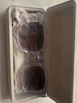 Transparenta fyrkantiga solglasögon från Chimi! - Säljer ett par trendiga solglasögon med transparent, fyrkantig båge och mörka glas. Snygg accessoar som ger en cool vibe till din outfit. Kommer i ett stilrent fodral. Använda typ två gånger!