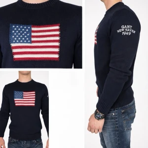 GANT Knit Sweater – American  (L, fits M) - GANT Knit Sweater – American Sportswear (L, fits M)  GANT knit sweater in a classic American sportswear style. Made from 100% cotton with a structured yet comfortable knit. Navy blue base featuring a knitted American flag on the chest and GANT New Haven 1949 embroidery on the sleeve. Tagged size L but fits closer to a modern Medium. Timeless design and solid quality. Feel free to get in touch with us if you have any questions.