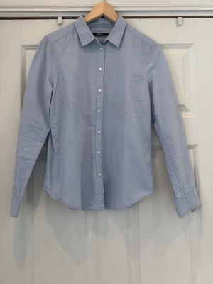 Ljusblå skjorta från Gina Tricot - Stilig och lyxig ljusblå skjorta från Gina Tricot . Skjortan är tillverkad i ett mjukt bomullstyg. Perfekt för en clean och stilren look, perfekt till ett par jeans eller annat, minimalt använd( mycket liten storlek 40, skulle säga S) ✨