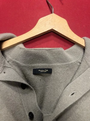 Ljusgrön stickad tröja med krage - Ljusgrön stickad tröja från Massimo Dutti med lång ärm och bred krage med knappar. Tröjan har ribbade muddar vid ärmslut och nederkant, vilket ger en snygg och avslappnad look. Perfekt för lager-på-lager-stil.