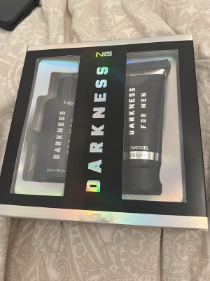 NG Darkness parfymset för män - Snyggt parfymset från NG med doften Darkness for Men. Setet innehåller en eau de toilette och en matchande showergel, båda i svart och silver förpackning. Perfekt presentförpackning med modern, holografisk design.