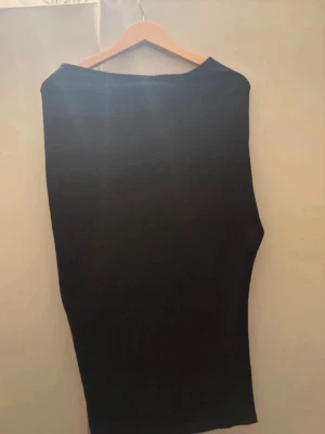 Svart långkjol med slits - En svart långkjol i stretchigt material med en snygg slits på sidan. Kjolen har en enkel och stilren design som passar till många olika looks. Perfekt för dig som gillar minimalistisk stil och vill ha en kjol som är lätt att matcha.