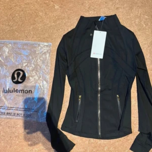 Define jacket från  Lululemon - Snygg svart träningsjacka från Lululemon med figurnära passform, hel dragkedja framtill och två fickor med guldfärgade dragkedjor. Aldrig använd, lappen är kvar på och påsen som den kom i finns kvar🩷🩷🩷 strl:4