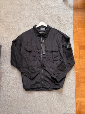 Stone Island overshirt - Snygg stone Island overshirt i svart färg. Det är en kompis som blev besviken eftersom den var för stor för honom.😥.  Kontakta om ni har frågor🤗 Ni får med ett LV bälta för 140 kr extra🤗