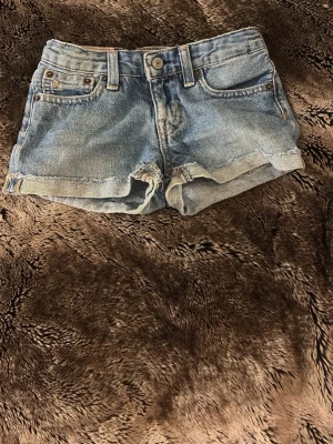 Blå jeansshorts från Polo Ralph Lauren - Snygga blå jeansshorts från Polo Ralph Lauren. Passformen är liten. 