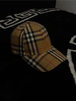 Burberry keps  - Säljer en burberry keps som knappast har används utan endast prövats ett fåtal gånger, den är i helt nytt skick och passar alla huvudformer, den är alltså anpassbar 