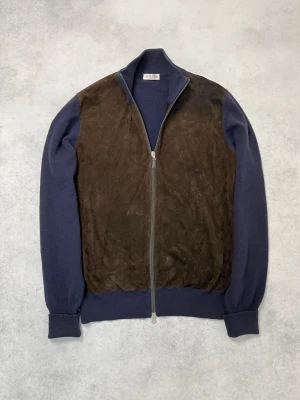 Blå ziptröja med mockadetaljer från Gran sasso - Snygg blå ziptröja från Gran Sasso med bruna mockadetaljer på framsidan. Tröjan har hög krage, långa ärmar och muddar vid ärmslut och nederkant. Perfekt för dig som gillar en unik och stilren look.