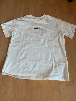 Maison Margiela T-shirt - Säljer denna stilrena Maison margiela T-shirten. Den är större i storlek upp till M-L⚪️ Ifall ni tvivlar på storlek skickar jag mått!!😁🙌