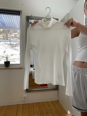 Vit polotopp i bomull - Klassisk vit polotopp med lång ärm i mjukt bomullsmaterial. Enkel och stilren design som passar till allt. Perfekt att bära som lager eller för en clean look.