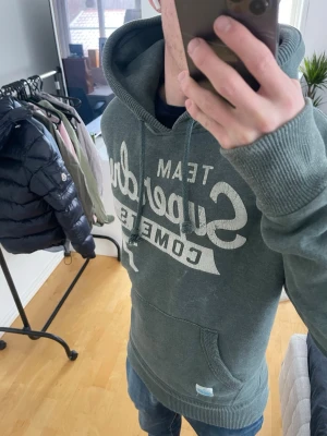 Grön Vintage 2000s Superdry Hoodie (Limited edition) - Säljer nu denna sjukt snygga och sällsynt vintage 2000s Superdry Hoodie! Sjukt snygg grön färg och perfekt passform😊 Hoodien är ur en limiterad upplaga med endast ca 900 sålda 🙌 Både mjuk och bekväm och passar perfekt nu mot våren🤝 Passar storlek L eller en stor M 🤩 Skriv vid funderingar 📲