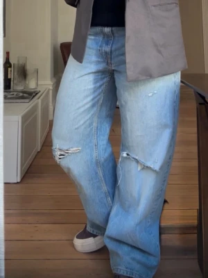 Ljusblå baggy jeans från Zara - Säljer ett par ljusblå baggy jeans från Zara med slitna detaljer och hål vid knäna. Jeansen har en avslappnad passform, hög midja och klassiska fem fickor. Använda en gång 🖤 