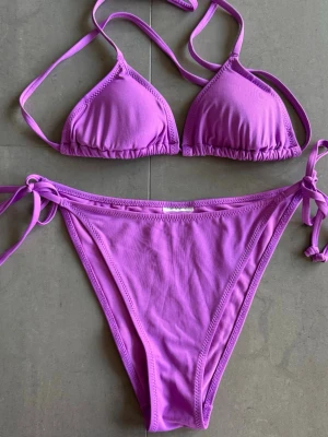 Lila bikini från H&M - Lila bikini från H&M. Lapparna är borta men tror att toppen är i 34 och nederdelen i 36/38. Eftersom man knyter både toppen och nederdelen kan man justera storlek i väldigt stor mån. 🌸 Oanvända. Nypris ca 250 kr.
