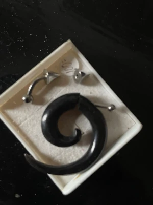 Svart spiralformad piercing - Cool spiralformad piercing i svart, troligen tillverkad av akryl eller plast. Passar som smycke för örat eller annan piercing. Snygg och unik design som sticker ut.