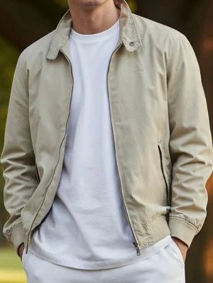 Beige vindjacka från Park Lane, Storlek XL - Stilren beige vindjacka från Park Lane med dragkedja framtill, två sidofickor och ribbade muddar. Jackan har klassisk krage med knappdetalj och diskret broderad logga på bröstet. Perfekt för en avslappnad look.                            1 