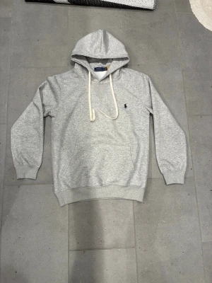 Grå polo hoodie  - Säljer nu denna feta polo tröjan som är väldigt snygg. Skick 9/10 storlek S             Mitt pris e 599 men kan diskuteras vid snabb affär, kom gärna vid fundering o lägg gärna ett prisförslag 