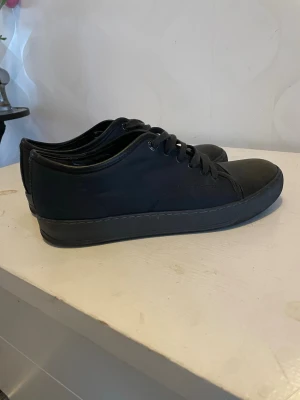 Lanvin  - Stilrena mörkblå lanvin med lågt skaft och klassisk snörning. Skorna är tillverkade i textil med matchande svart sula och diskret design. Perfekta för en clean och enkel look. Snöret är trasigt men det syns inte. Det finns ingen box eller kvitto skriv vid frågor osv