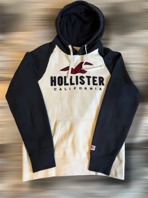 Hollister hoodie med Mörkblå armar M - Snygg hoodie från Hollister med svart huva och ärmar samt vit framsida. Riktigt snygg och passar till allt! Tveka inte på att höra av er vid frågor!⭐️