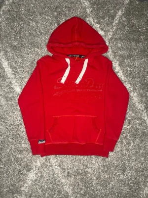 Superdry hoodie röd - Väldigt fin Superdry hoodie i färgen röd. Den är storlek M och den är i toppskick. Skriv gärna vid minsta intresse, passar perfekt nu till våren 