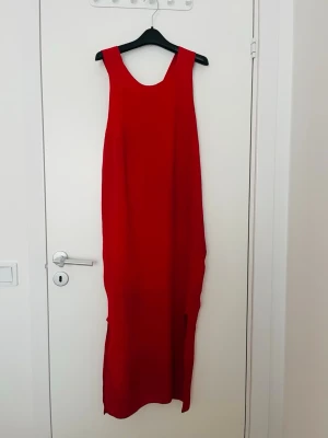 Mango Röd ärmlös långklänning - Snygg röd långklänning med ärmlös design och rund halsringning. Klänningen har en rak och enkel siluett med en liten slits nertill. Perfekt för dig som vill sticka ut med en stark färg. Materialet känns lätt och luftigt.