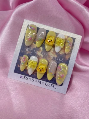 HoneyBear (XS);Medium Almond - Unika handgjorda press-on naglar i gult och vitt med 3D-rosetter, söta 🐻Nalle Puh och färgglada detaljer. Medium almond form, handgjorda i XS: 14 mm, 11 mm, 11,5 mm, 10 mm, 8 mm. Perfekt för dig som vill ha något lekfullt och kreativ solekänsla på naglarna.