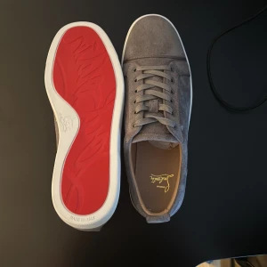 Gråa sneakers från Christian Louboutin - Säljer ett helt nytt par Christian Louboutin i grå mocka färg, perfekt för dug som vill ha en stil ren look och vill att folk ska vända sitt huduvd nör du lyfter fötterna (pris kan ändras vid snabb affär!!)