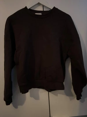 Svart basic sweatshirt - En enkel svart sweatshirt med rund hals och långa ärmar. Tröjan har ribbade muddar vid ärmslut och nederkant. Perfekt för en avslappnad och stilren look. Materialet känns mjukt och bekvämt mot huden.