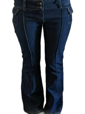 Mörkblå bootcut jeans med detaljer - Säljer ett par mörkblå låg midjade bootcut jeans med coola fickor från Brandy Melville. Klassisk denimlook i mjukt bomullsmaterial. Storlek S men ganska stretchiga! Skriv för mått osv!🙏💕