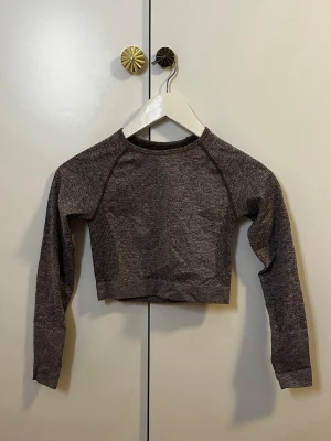Mörkgrå croppad träningstopp - Snygg mörkgrå croppad topp med lång ärm och rund hals. Tight passform och diskret mönster i tyget för extra stilpoäng. Storlek S.                                                                       Hör av dig vid frågor!☺️