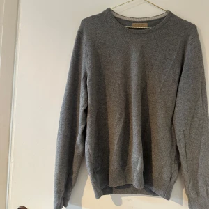 Grå cashmere-tröja från Falconeri - Mjuk och stilren grå stickad tröja från Falconeri i 100% cashmere. Tröjan har rund halsringning, långa ärmar och ribbade muddar vid ärmslut och nederkant. Perfekt för dig som gillar klassisk och enkel stil.