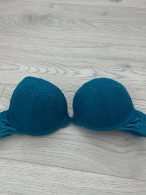Turkos spets-bh med vaddering - Snygg turkos bh med vadderade kupor och spetsdetaljer på framsidan. Bh:n har bygel och justerbara axelband för bästa passform. Materialet är mjukt och bekvämt, perfekt för dig som vill ha både stöd och stil.