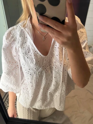 Vit blus - Säljer en vit blus med trekvartsärmar. Blusen har v-ringning med knytband.