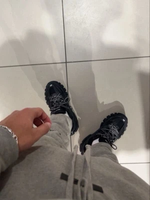 Balenciaga  - Säljer ett par Balenciaga Track sneakers i helsvart med chunky sula och detaljerade paneler i mesh och syntet. Skorna har reflekterande detaljer och dubbla snören för en unik look. Perfekta för dig som vill sticka ut med streetwear-vibe.