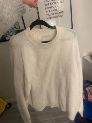 Vit stickad tröja - Mysig vit stickad tröja med rund halsringning och avslappnad passform. Tröjan har långa ärmar och ribbade muddar vid hals, ärmslut och nederkant. Perfekt för lager på lager och enkel att matcha med olika stilar.