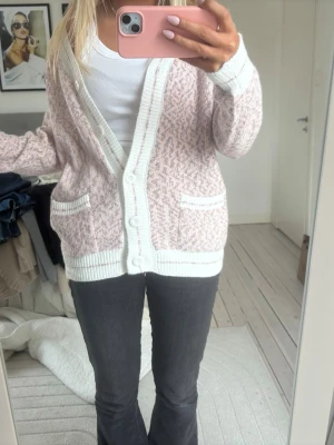 Ljusrosa kofta med mönster - Mysig ljusrosa kofta med vitt mönster och breda vita ribbade kanter. Den e så skön och så fin i färgen! Köpt från Frankrike!
