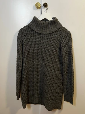 Grå poloklänning från Dobber - Mysig grå stickad poloklänning (minidress) från Dobber med grovstickad struktur och hög krage. Tröjan har långa ärmar och ribbade muddar vid ärmslut och nederkant. Hör av dig om du har frågor!☺️
