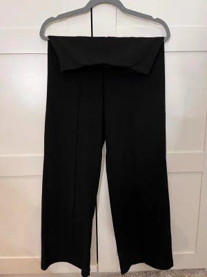 Svarta vida kostymbyxor - Säljer ett par svarta kostymbyxor med hög midja och vida ben från VERO MODA. Byxorna har pressveck framtill för en clean look och är sydda i ett mjukt, vävt tyg som ger en snygg siluett. Perfekta till en dressad outfit. Spasamt använda och i fint skick. Nypris: 449.95kr Mitt pris: 200kr