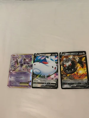 Pokémonkort samling V och GX - Säljer en samling Pokémonkort med motiv av Mewtwo, Togekiss V, Steelix V, Hatterene V och Metagross GX. Korten har färgstarka illustrationer och holografiska effekter. Perfekt för samlare eller Pokémon-fans som vill utöka sin kortsamling.