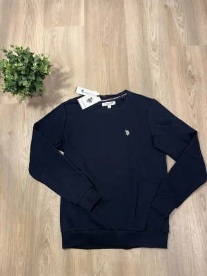 Mörkblå sweatshirt från U.S. Polo Assn. - Säljer nu en marinblå U.S Polo Assn. sweatshirt som är helt ny. Den är sjukt skön då den har väldigt mjukt och gosigt matrial invändigt. Den har lappar och allt kvar (endast testad) Ny pris 549kr  Som vanligt är priset inte hugget i sten och tveka inte på att höra av dig vid frågor och funderingar.