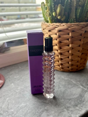 valentino purple melancholia 10ml - valentino purple melancholia Eau de Parfum i en 10 ml sprayflaska med coolt nitat mönster. Flaskan är transparent med svart sprayhuvud och kommer i en lila kartong med elegant design. Perfekt att ha med i väskan för en lyxig touch. Ny 