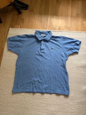 Lacoste piké - Säljer denna Lacoste piké tröjan som är i mycket bra skick. Nypris: 1099kr Storlek: L Mått: Axel-Axel 44cm Armhåla-Armhåla 51cm Längd 64cm