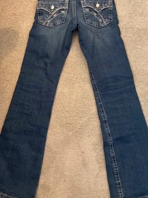 Bootcut jeans, blåa strl 152 från Gina Tricot. - Jag säljer ett par blåa bootcut jeans från Gina Tricot. Använt dem några få gånger och är i  jätte bra skick. De har ett fint mönster på fickorna och är ett par trendiga jeans i strl 152.