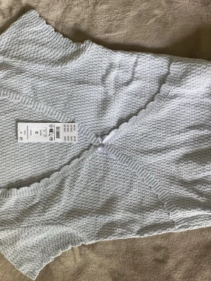Gullig stickad t-shirt - Ser grå ut på bilden men är mer ljusblå i verkligheten. Aldrig använd. Lite kort. Köpt på Gina tricot