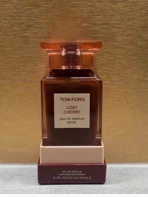Tom Ford Lost Cherry EdP 100 ml - Tom Ford Lost Cherry Eau de Parfum i 100 ml flaska. Flaskan är elegant och fyrkantig i mörkröd glas med en matchande röd kork. Märkets logga och doftens namn syns tydligt på etiketten framtill. En lyxig parfym som sticker ut i badrumshyllan.