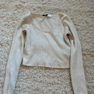Vit ribbstickad crop top - Trendig vit ribbstickad crop top med lång ärm och rundad urringning. Perfekt för lager på lager och enkel att matcha med olika stilar. Mjuk och stretchig kvalitet för en bekväm känsla.