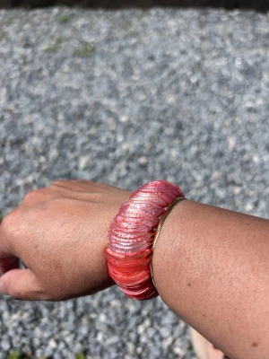 Armband med  snäckskalspärlor - Uniktarmband med skimrande rosa snäckskalspärlor i lager på lager-design. Armbandet har en elastisk tråd som gör det enkelt att ta på och av. Perfekt för dig som vill ha en färgklick till din outfit och gillar strandvibbar.