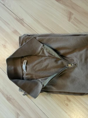 Beige kortärmad topp med dragkedja - Säljer en beige kortärmad pické från Jack & Jones med krage och half zip-dragkedja framtill. Materialet känns som bomull och den har en enkel, stilren look som passar till mycket.