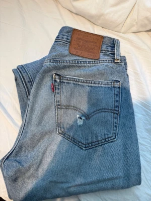 Levi's 551Z ljusblå raka jeans - Ljusblå raka jeans från Levi's modell 551Z med klassisk femficksdesign och läderpatch bak i midjan. Jeansen har en liten slitning på bakfickan och är tillverkade i slitstark denim. Perfekta för en avslappnad och trendig look.