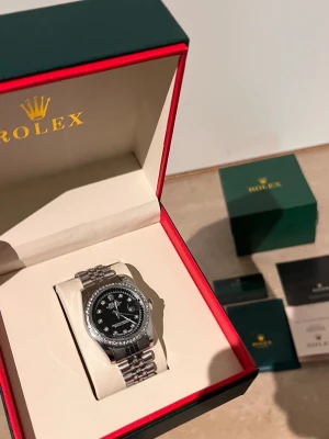Role silverklocka med svart urtavla - Stilren Role herrklocka i silver med svart urtavla och klassisk länkarmband. Klockan levereras i originalbox med tillhörande certifikat och manualer. Perfekt accessoar för dig som vill ha något exklusivt och tidlöst på handleden.