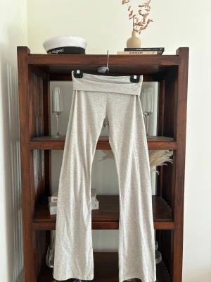 Gråmelerade bootcut leggings - Säljer ett par gråmelerade leggings med bootcut-ben och bred, vikt linning. Mjukt och stretchigt material som sitter skönt på kroppen. Perfekta för en avslappnad och trendig look.