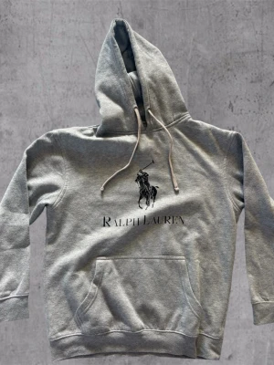 Grå hoodie från Ralph Lauren - Grå hoodie från Ralph Lauren, storlek M lappen i nacken är av FYI och den har lite tecken på användning men i övrigt bra skick 